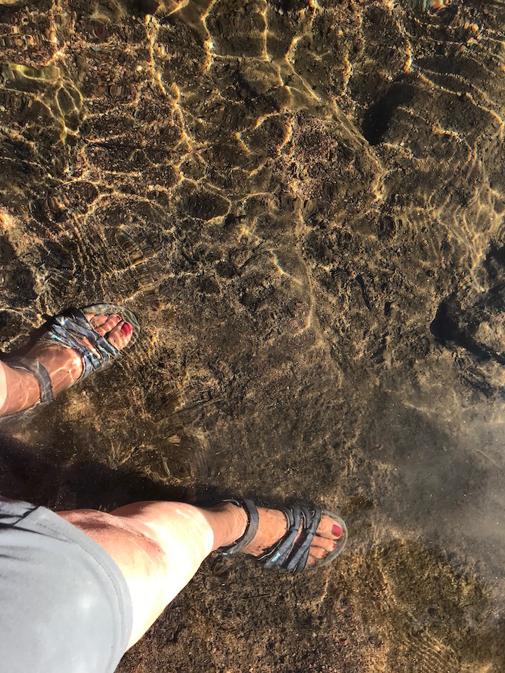 Sandaled feet in clear river water